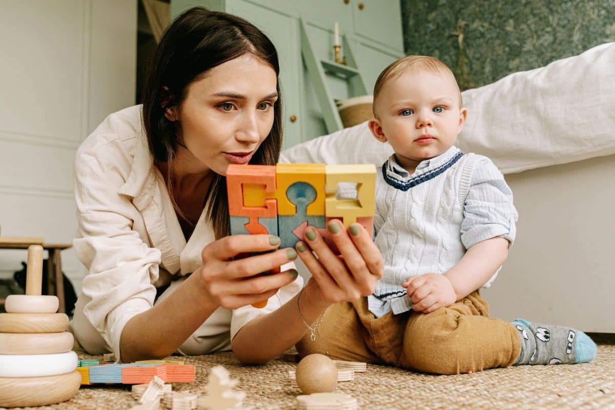 Mother playing with her toddler son using Montessori wooden educational toys to support early learning and focus