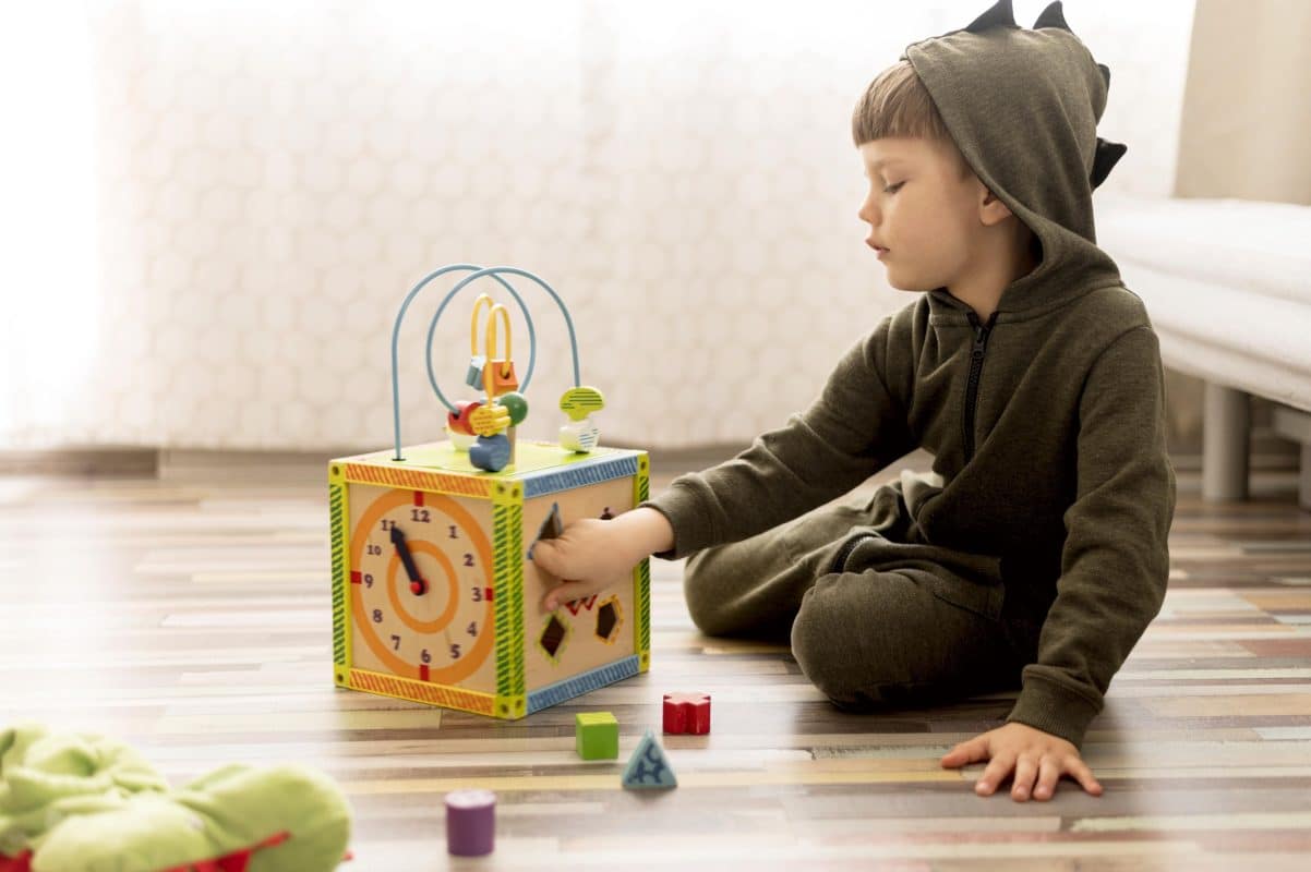 baby boy playing with montessori toy on the wooden floor