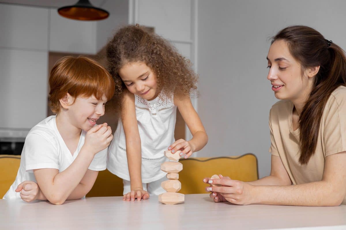 children with their mum building wooden balancing stones tower
